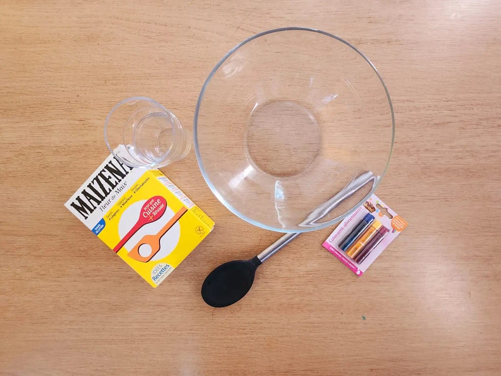 Matériel nécessaire pour réaliser l’expérience de la pâte magique : maïzena, bol, cuillère, colorants alimentaires et eau.