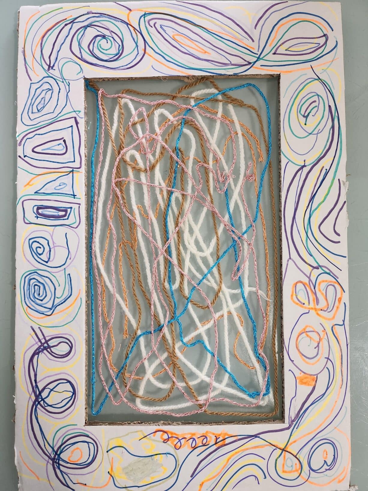 Cadre créatif décoré de dessins au feutre et de fils de laine tendus sur un film transparent