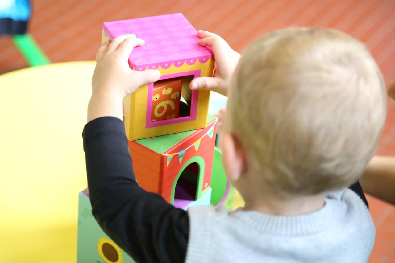 Un enfant jouant avec des cubes colorés, activité d'éveil chez une assistante maternelle