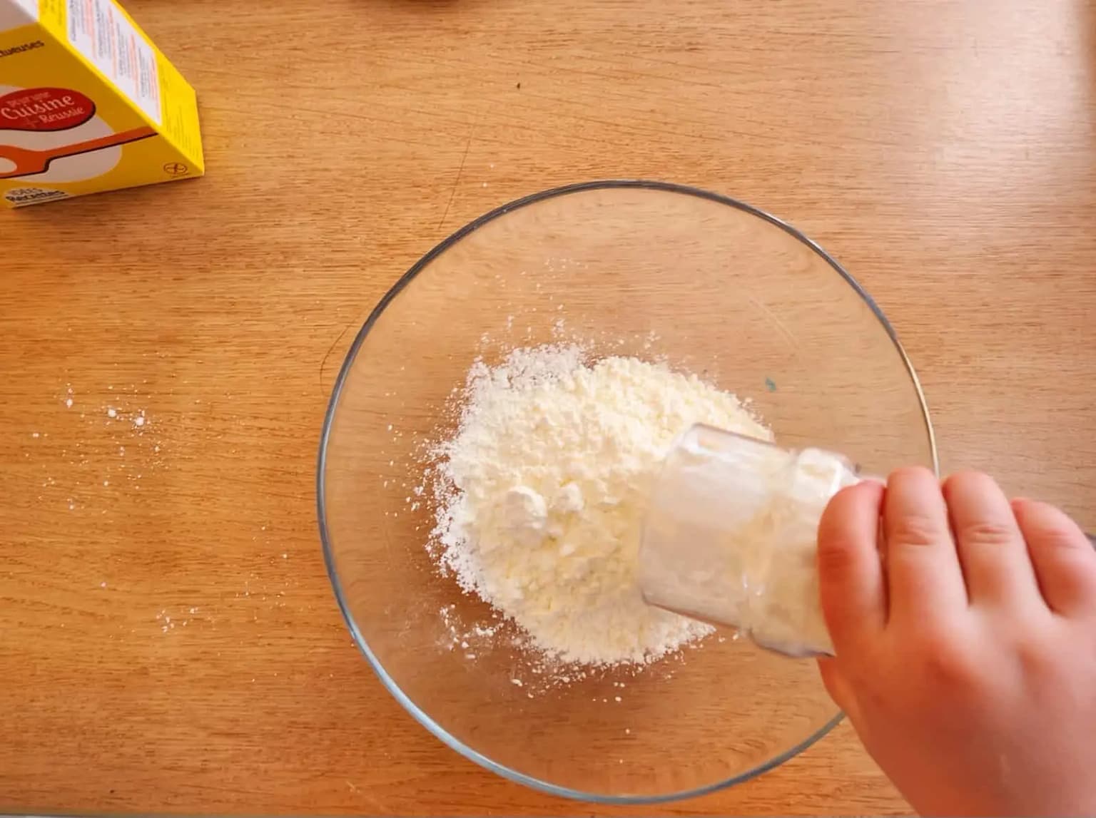 Un enfant verse de la maïzena dans un bol pour préparer une pâte magique oobleck
