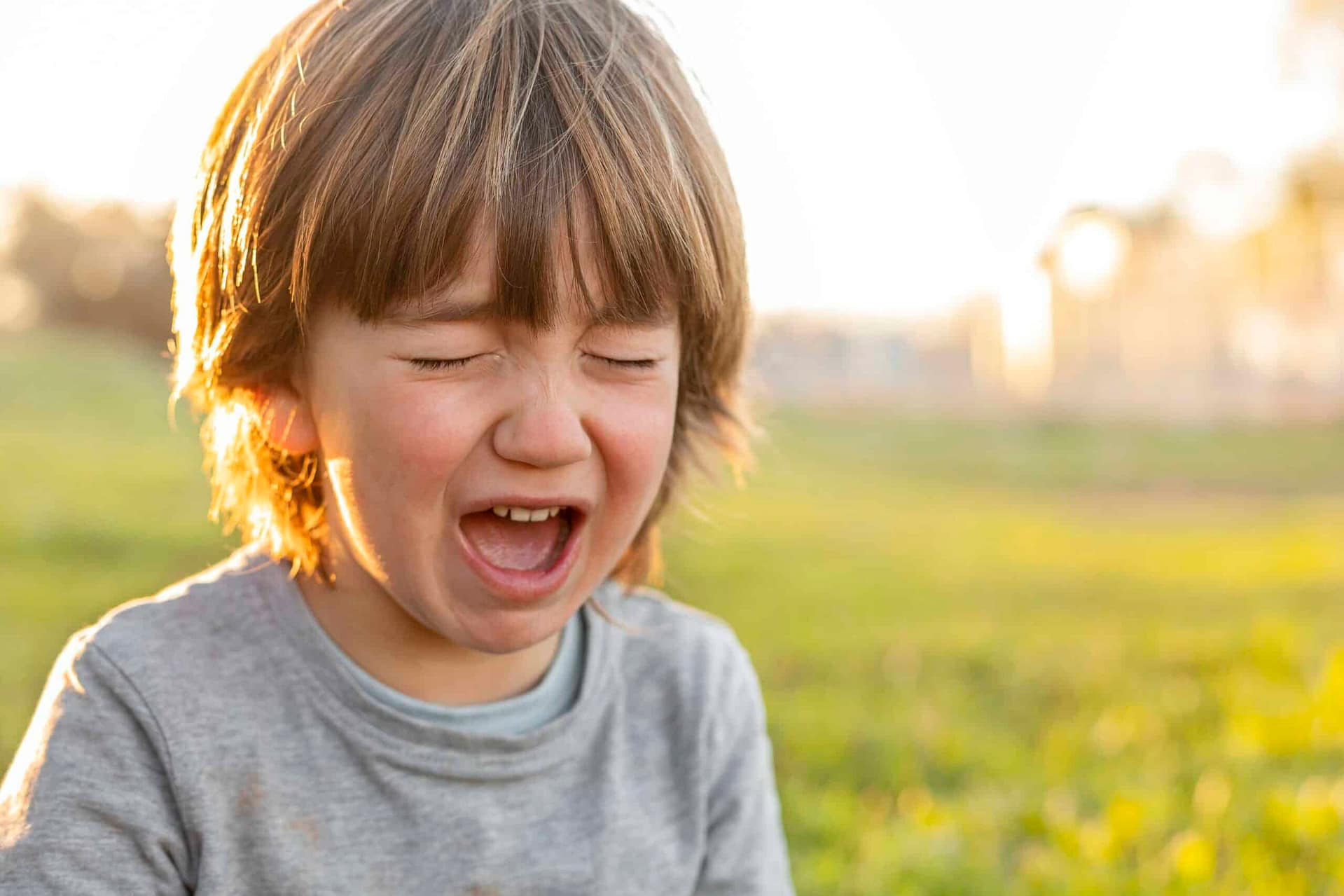 Un enfant assis dans un parc, pleurant, illustrant une situation de frustration ou de déception.