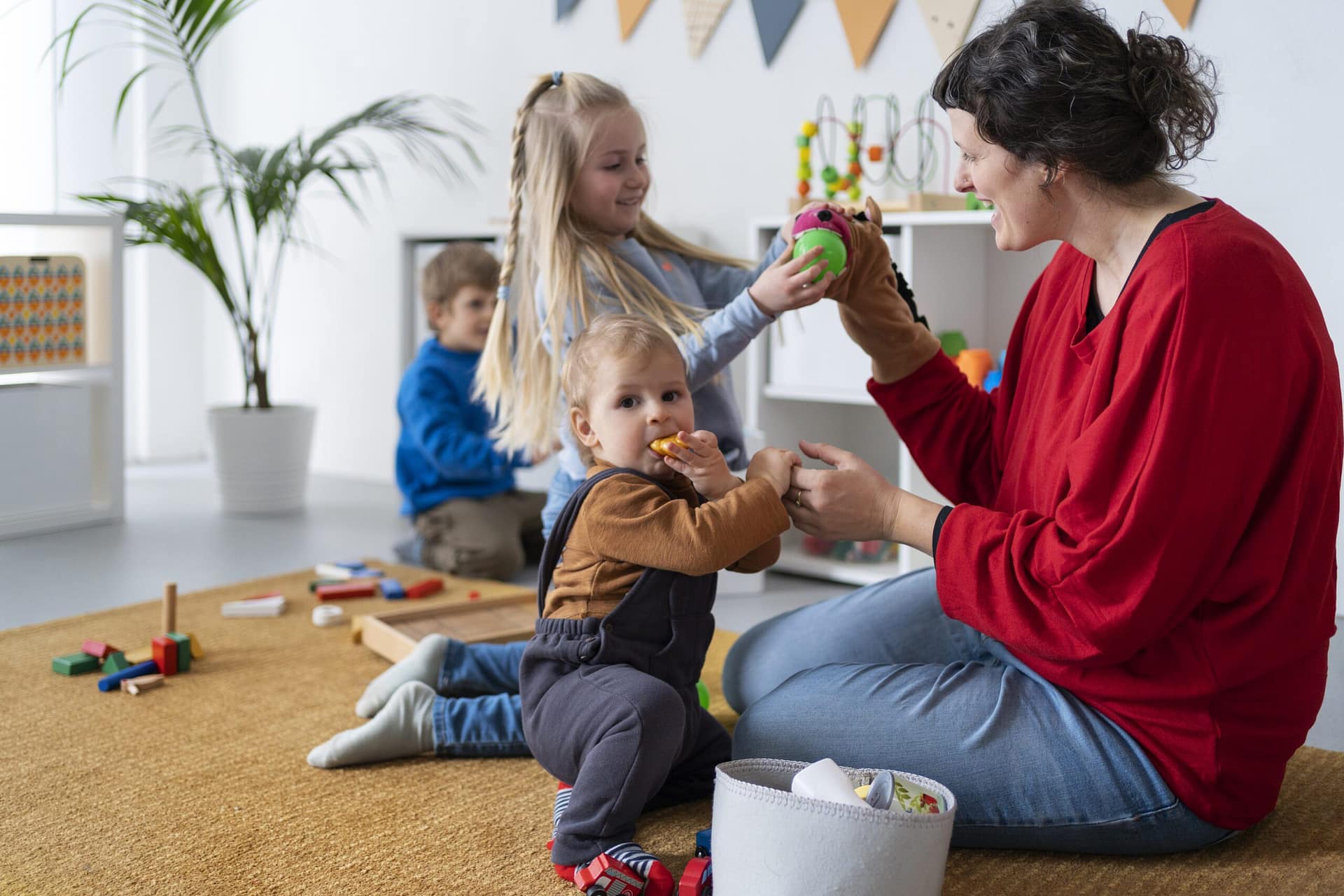 Assistante maternelle agréée jouant avec des enfants dans un espace d'accueil sécurisé, stimulant leur éveil avec des jeux éducatifs.