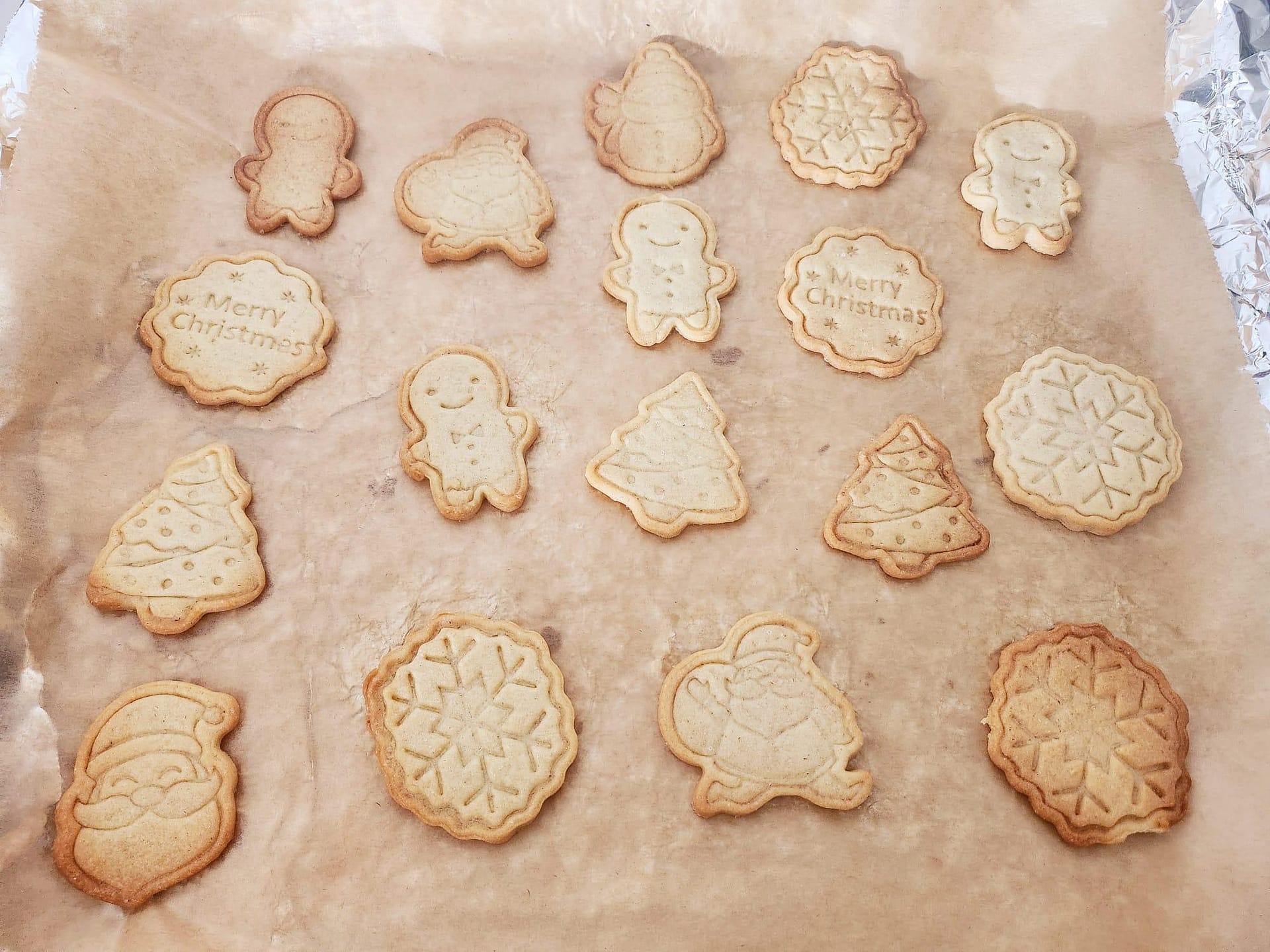 Sablés de Noël pour les enfants. Une plaque de cuisson remplie de sablés de Noël dorés, en forme de bonhommes, sapins et étoiles.