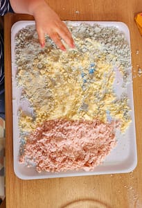Sable cinétique coloré fait maison sur plateau sensoriel, activité ludique pour enfant