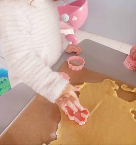 Une petite fille utilise un emporte-pièce festif pour découper des formes dans la pâte à sablés.