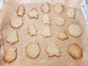 Sablés de Noël pour les enfants. Une plaque de cuisson remplie de sablés de Noël dorés, en forme de bonhommes, sapins et étoiles.