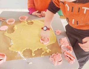 Un enfant utilise un emporte-pièce pour découper des formes festives dans une pâte à sablés de Noël