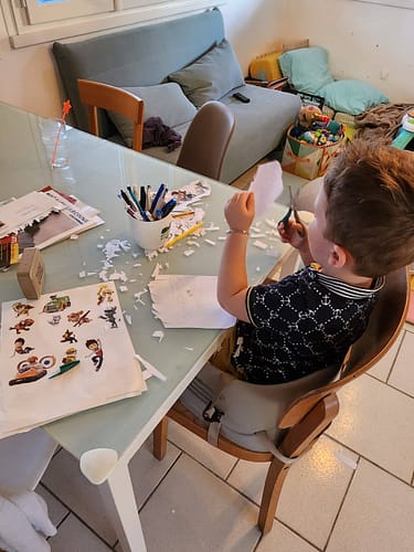 Enfant en train de découper du papier à une table d'activités