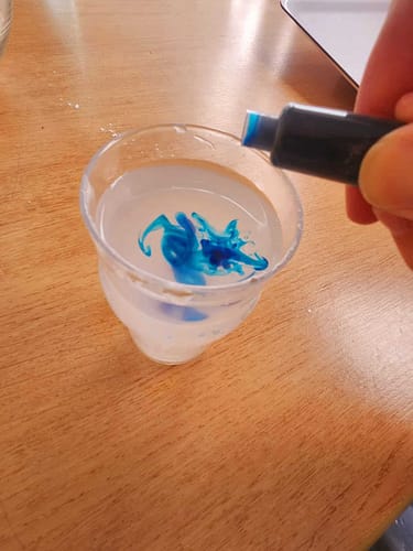 Ajout de colorant alimentaire bleu dans un verre d’eau pour préparer la pâte magique oobleck